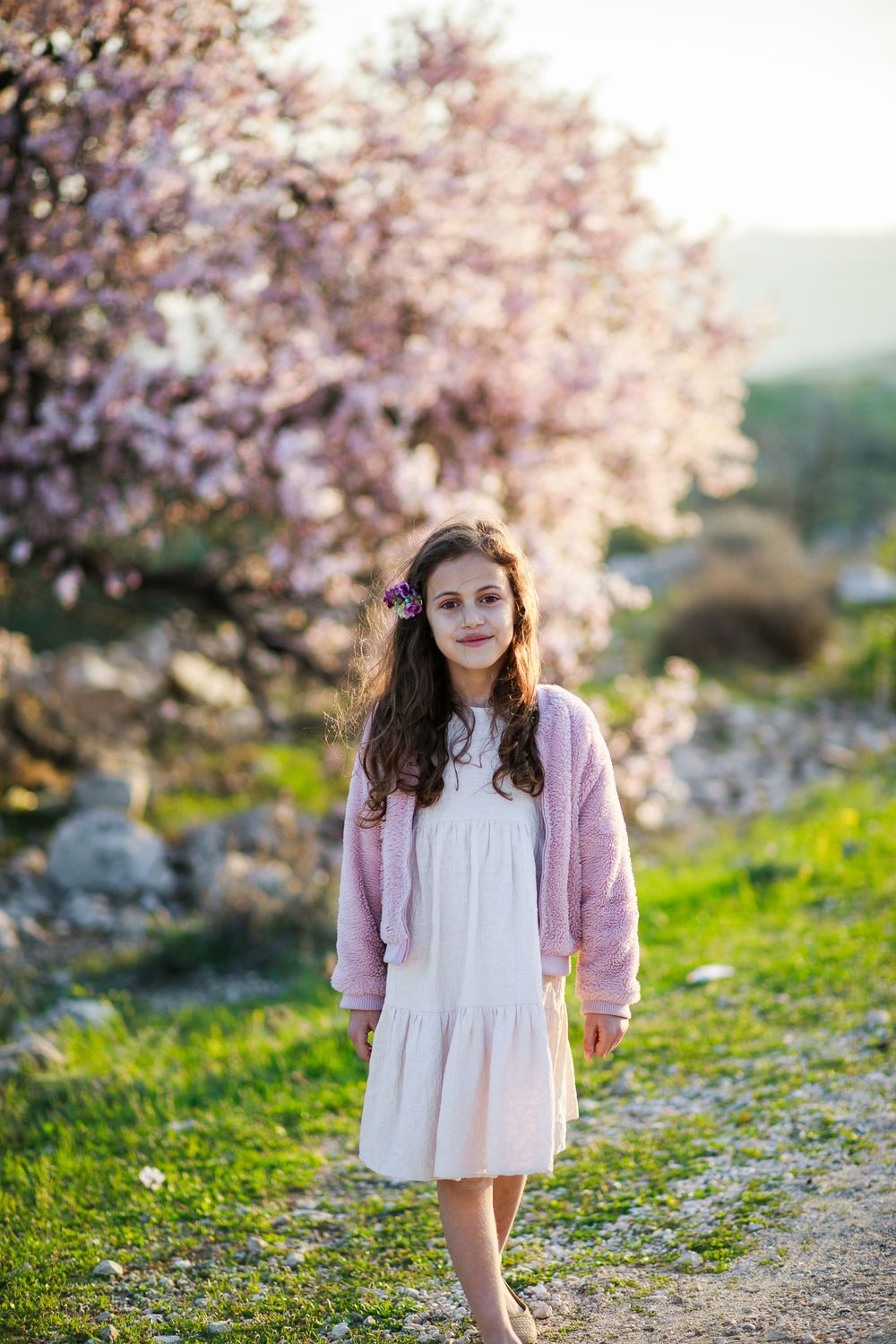 A girl walks by a pink almond tree