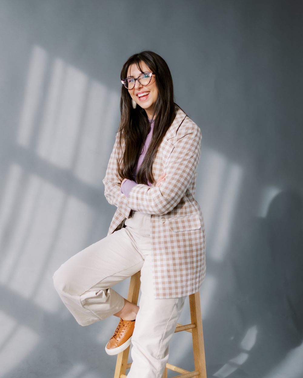 Fashion portrait featuring a cozy checkered jacket and white pants styled with casual sneakers in natural lighting.