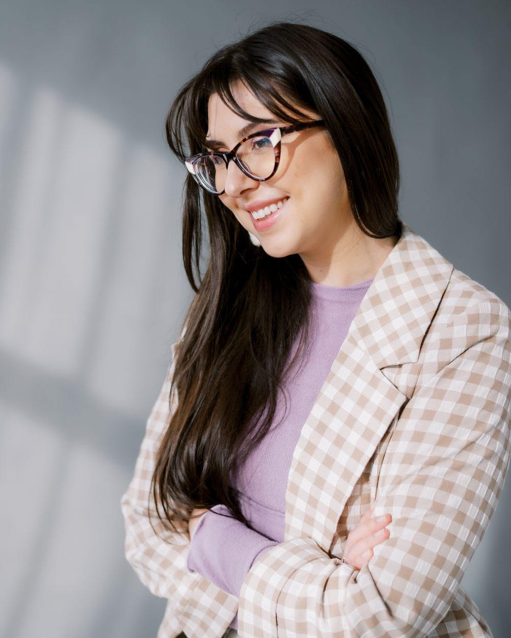 Modern fashion portrait with checkered blazer and lavender top in soft window lighting.
