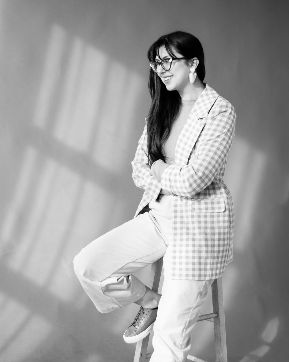 Black and white portrait highlighting modern casual style with gingham jacket and white pants.