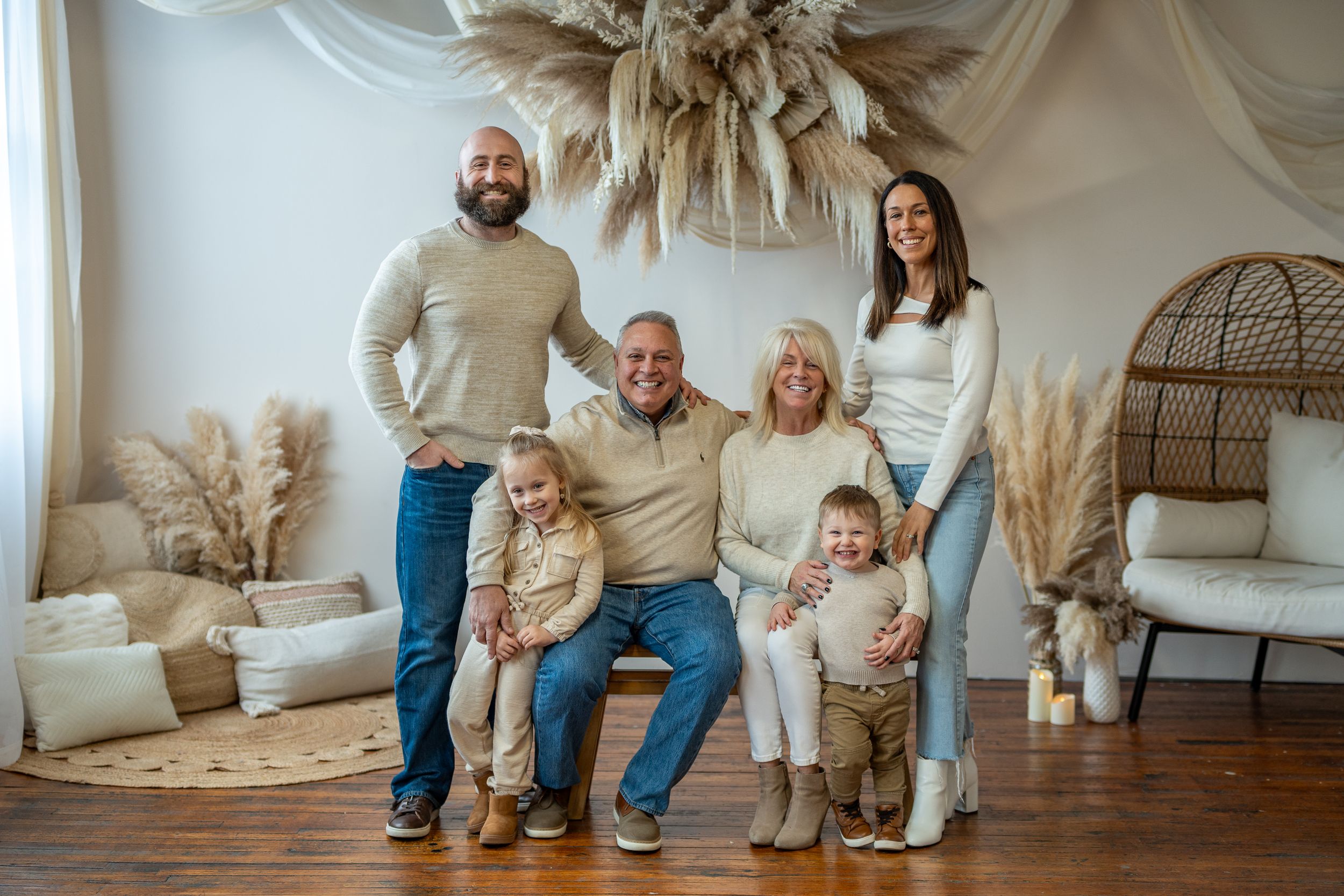 Family portrait in modern living room with pampas grass and wicker furniture.