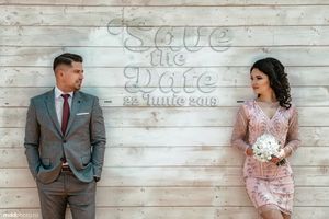 A stylish save the date photo against a rustic wooden wall backdrop.
