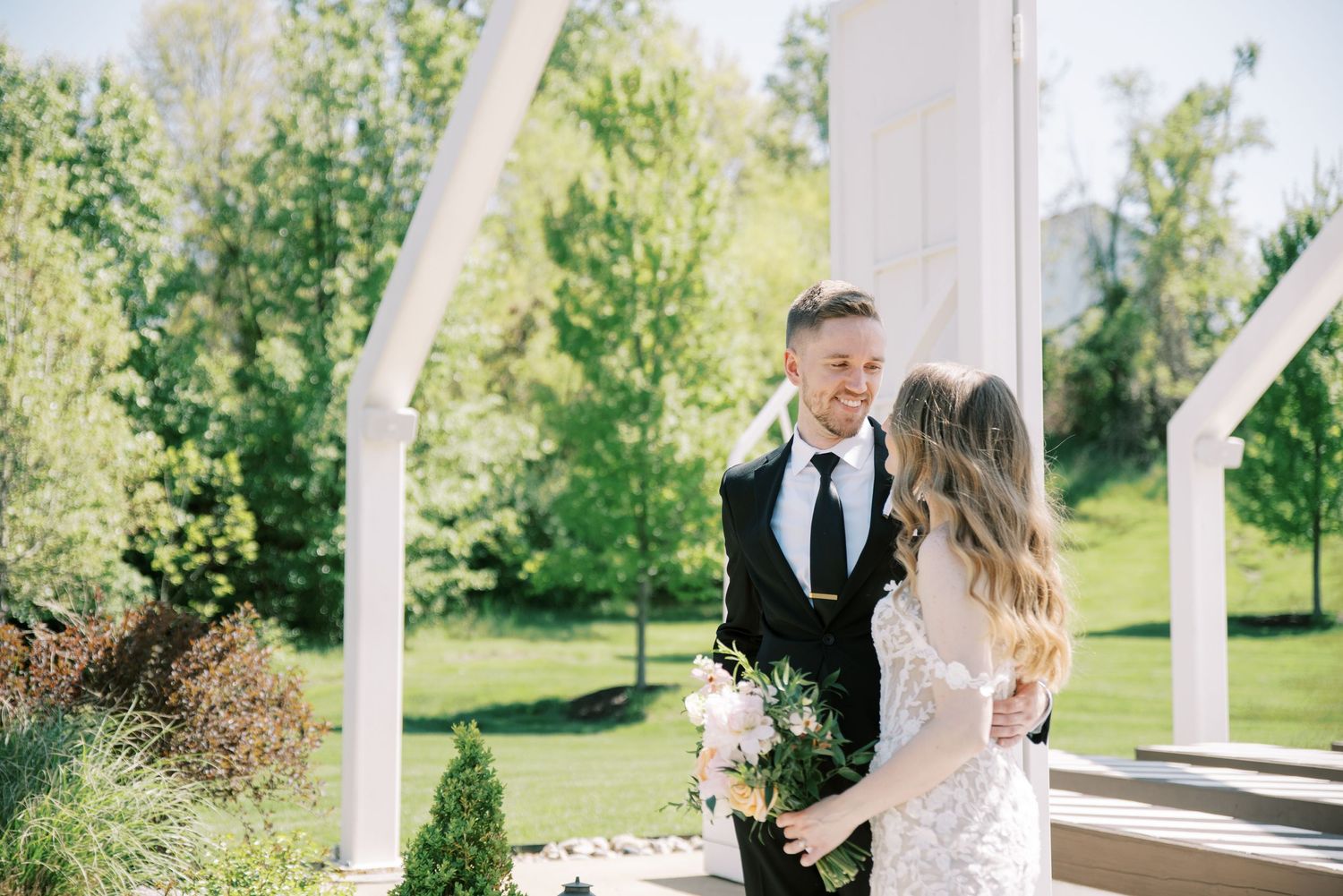 Wedding ceremony under white architectural beams in a beautiful outdoor garden setting.