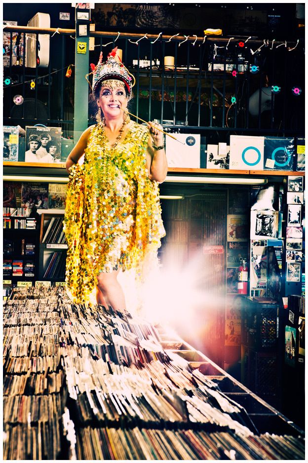Person in bright yellow sequined outfit browsing through vinyl records in a music store.