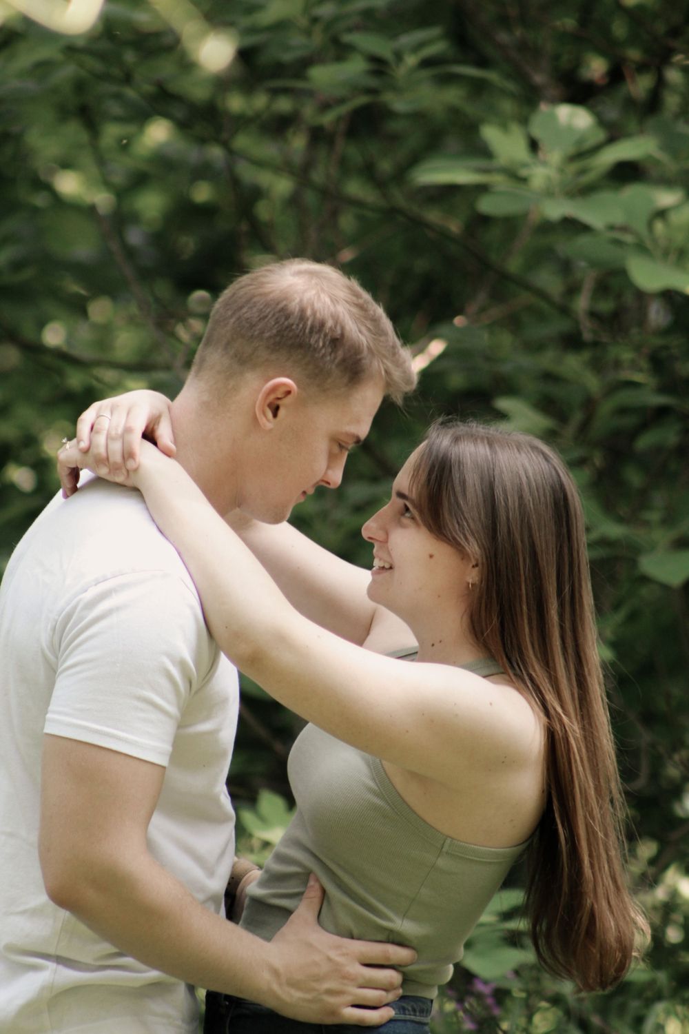 Two people dance closely together in a serene forest setting.
