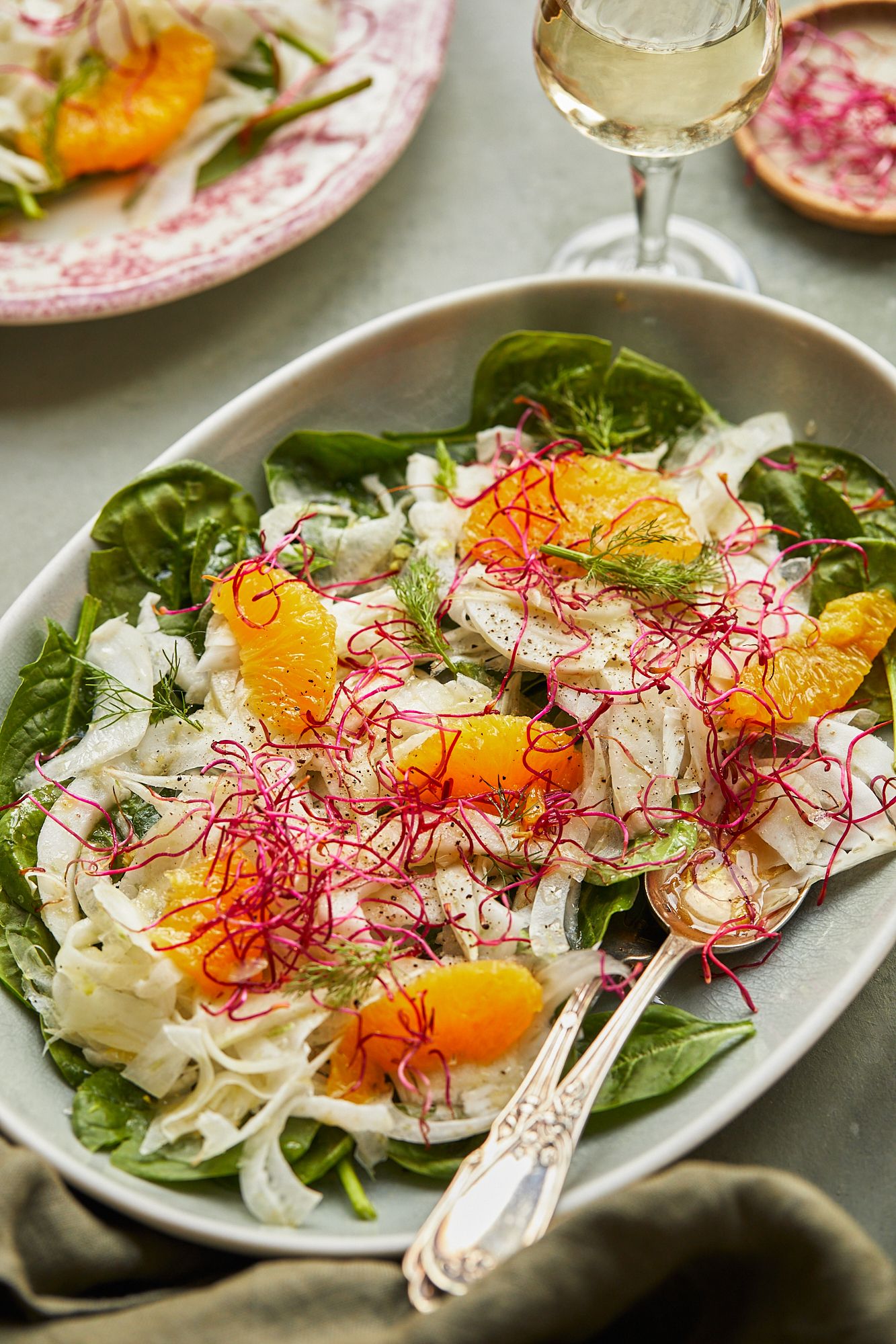 Elegant citrus and fennel salad with saffron threads and fresh herbs on oval platter.