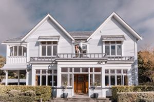 Bride and groom kissing on the balcony of a victorian era house on wedding day.