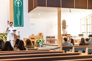 Church interior with wooden pews and religious service in progress.