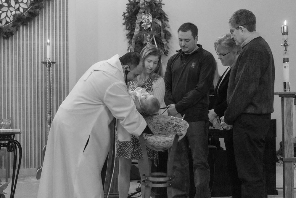 Religious ceremony taking place in church with holiday decorations.