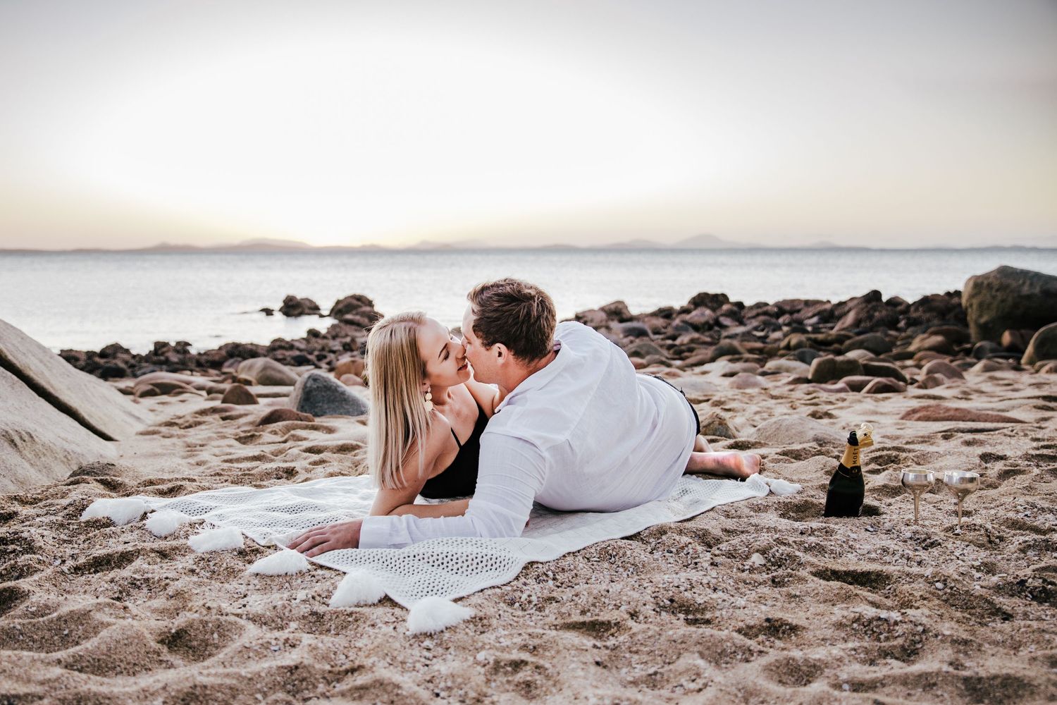 lady and man laying on a rug on the beach in an intimate setting