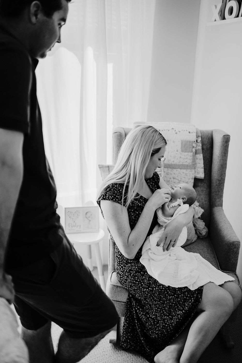 A couple spends time with their newborn baby in a bright, modern nursery.