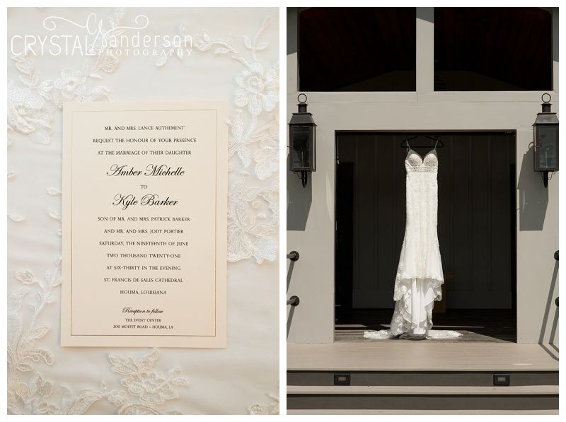 Wedding invitation suite and bridal gown hanging in window light.