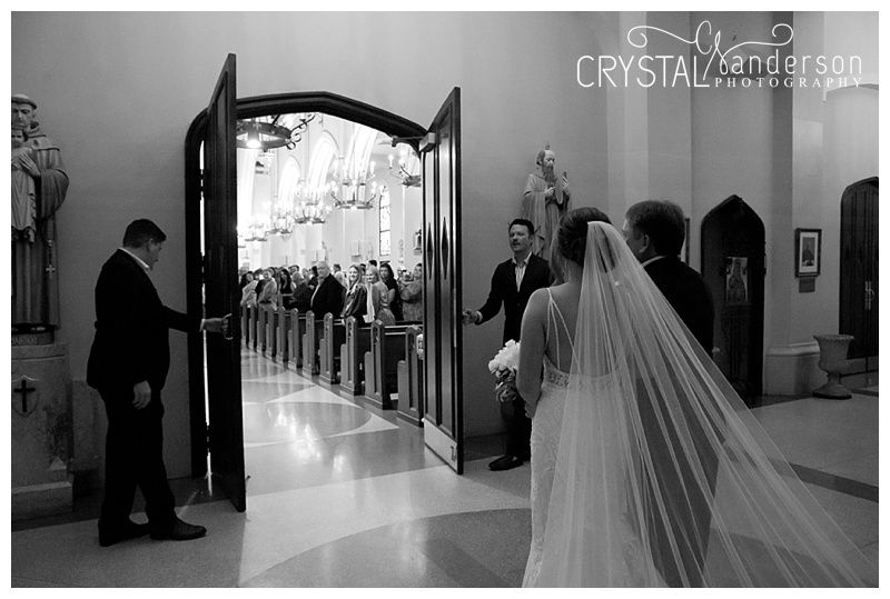 Church interior hallway with arched doorways and guests lining the aisle.