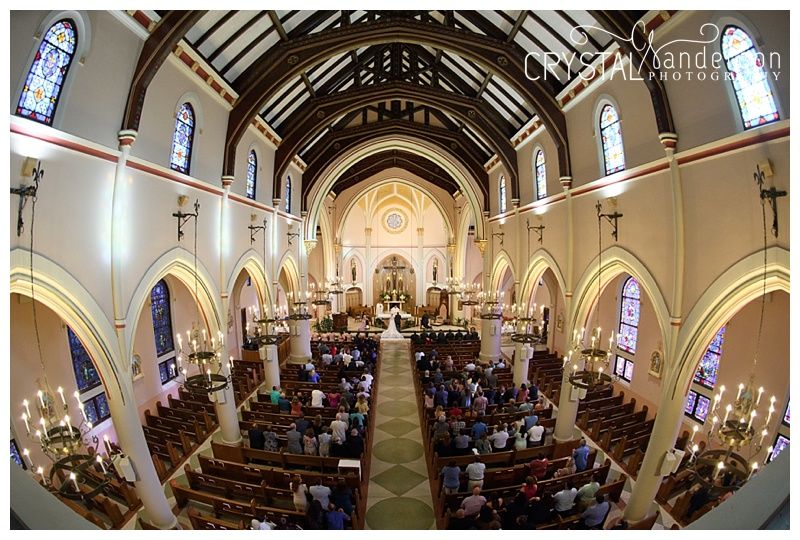 Wide angle view of a church sanctuary with vaulted ceilings and stained glass windows.