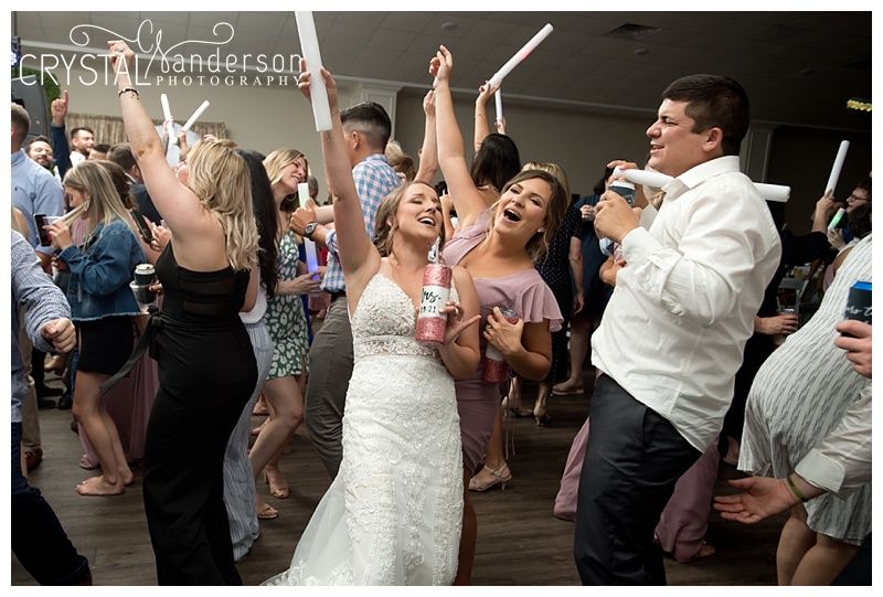 Wedding party dancing and celebrating with glow sticks on a dark dance floor.
