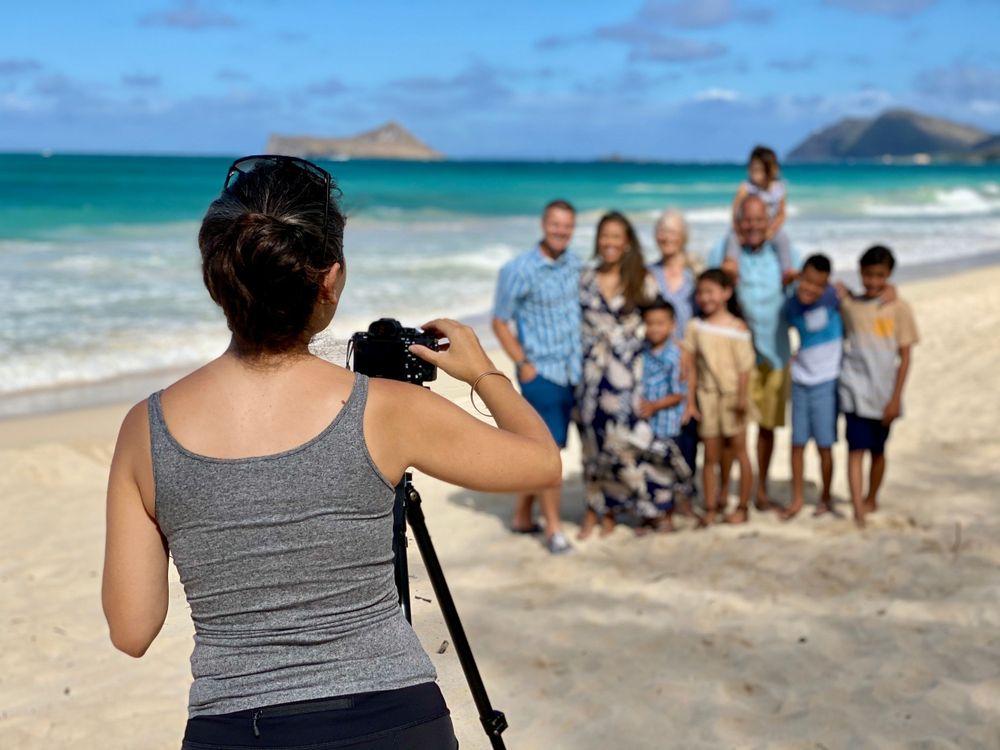 Photographer captures a group photo session on a tropical beach with turquoise water and mountains. Family Portraits