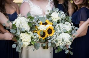 Wedding bouquets featuring white hydrangeas and bright sunflowers held by wedding party.