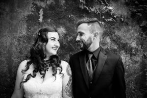 Black and white portrait of a couple sharing a tender moment against a textured wall.