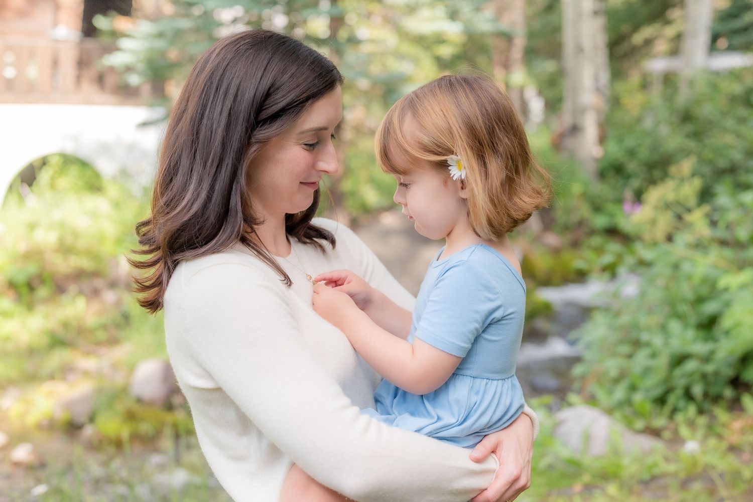 A tender moment between mother and child in a forest setting, showing gentle connection and care.