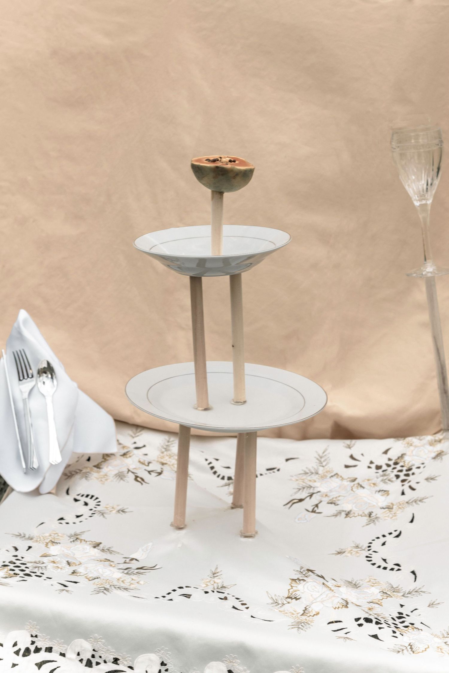 Minimalist white ceramic plates on stands arranged on a delicate lace tablecloth.