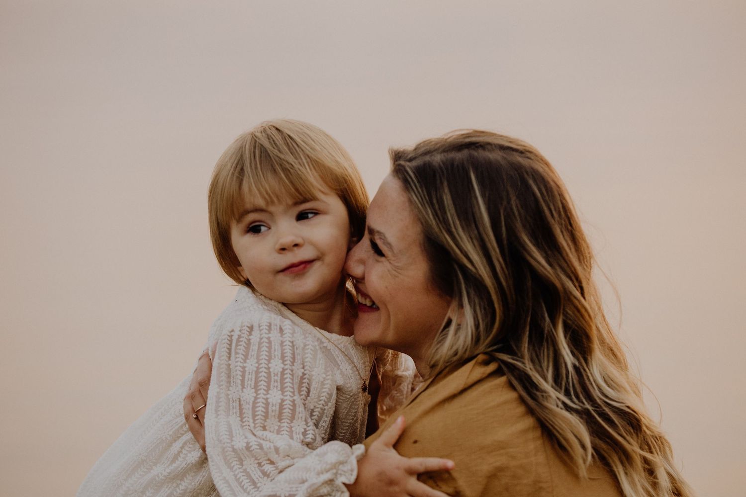 A tender moment shared between parent and child against a neutral background.