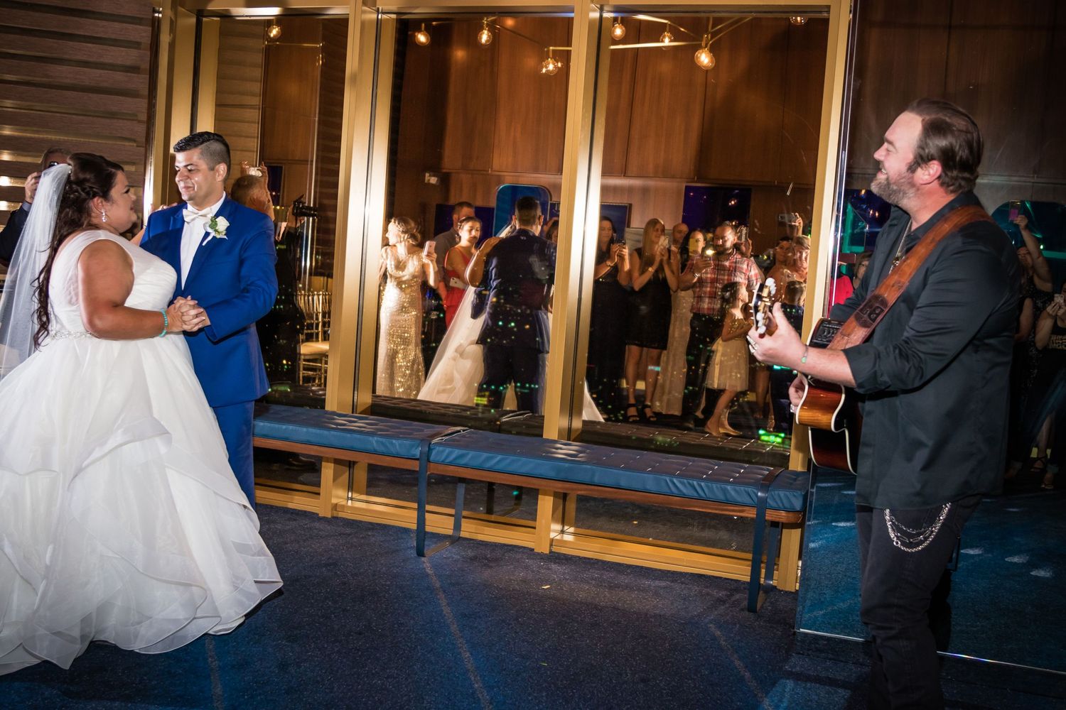Wedding celebration with dancing couple and live musician performing on stage.