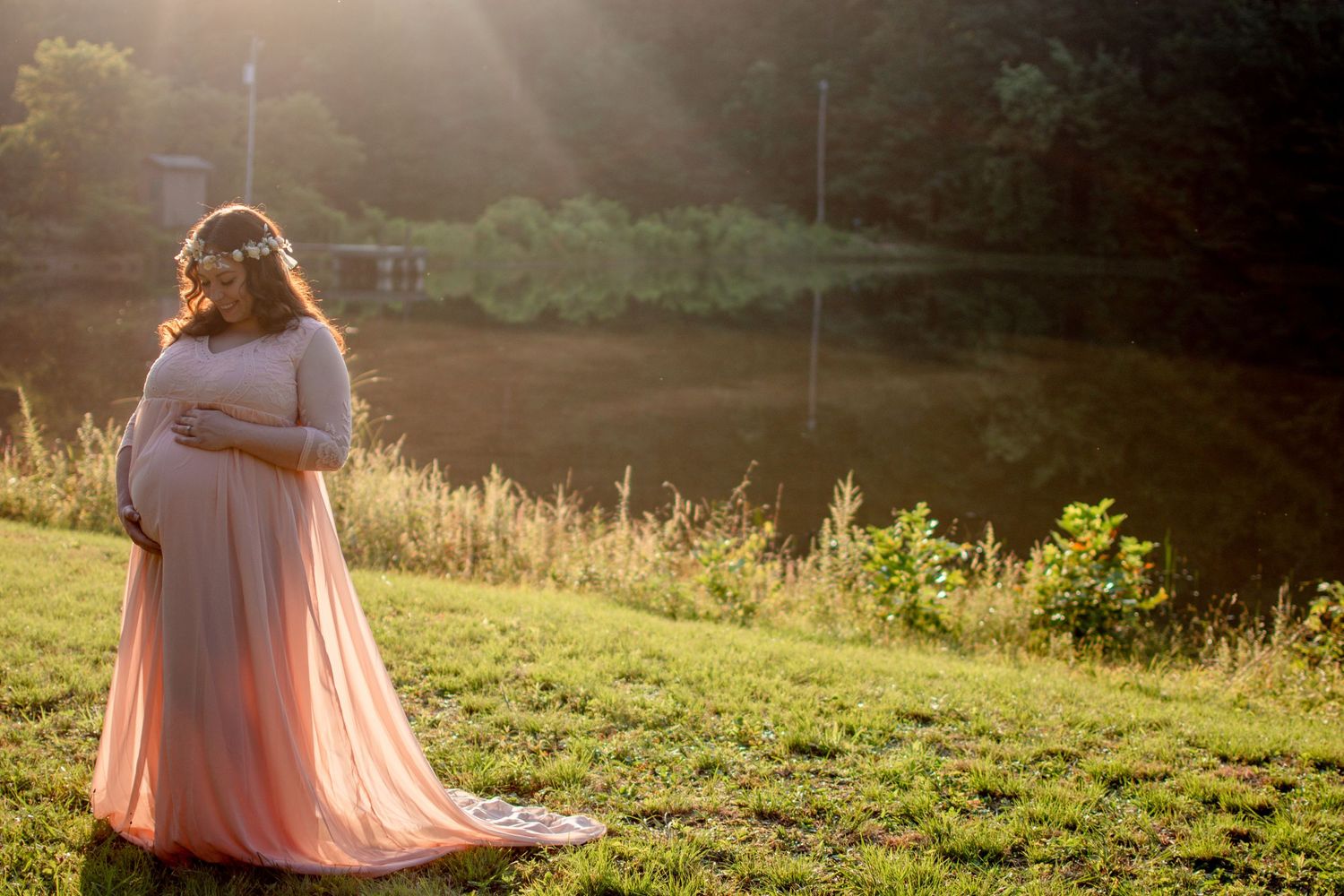 Ethereal maternity photo in a flowing pink dress at golden hour.