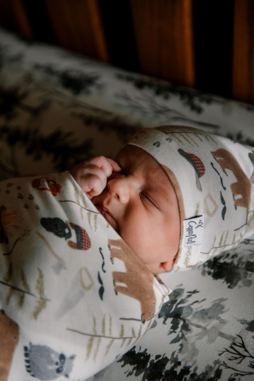 Sleeping newborn in white patterned outfit rests on floral bedding.