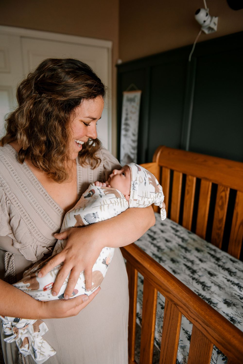 Intimate nursery moment with wooden crib and soft lighting.
