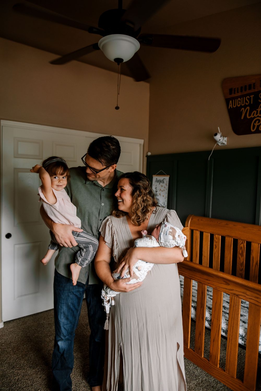 Family sharing tender moments together in nursery with wooden crib.