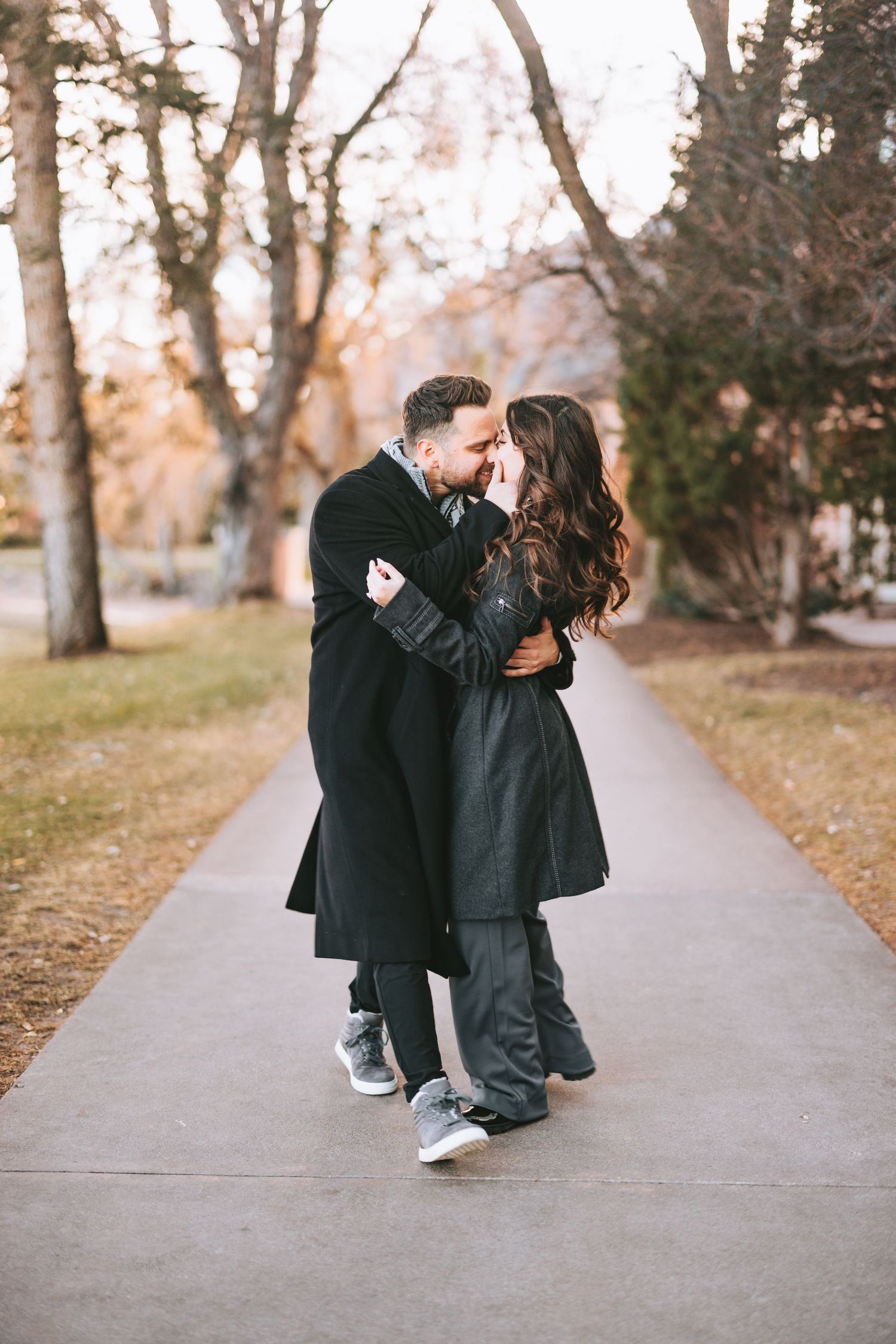 A romantic couple embracing on a park pathway during autumn.