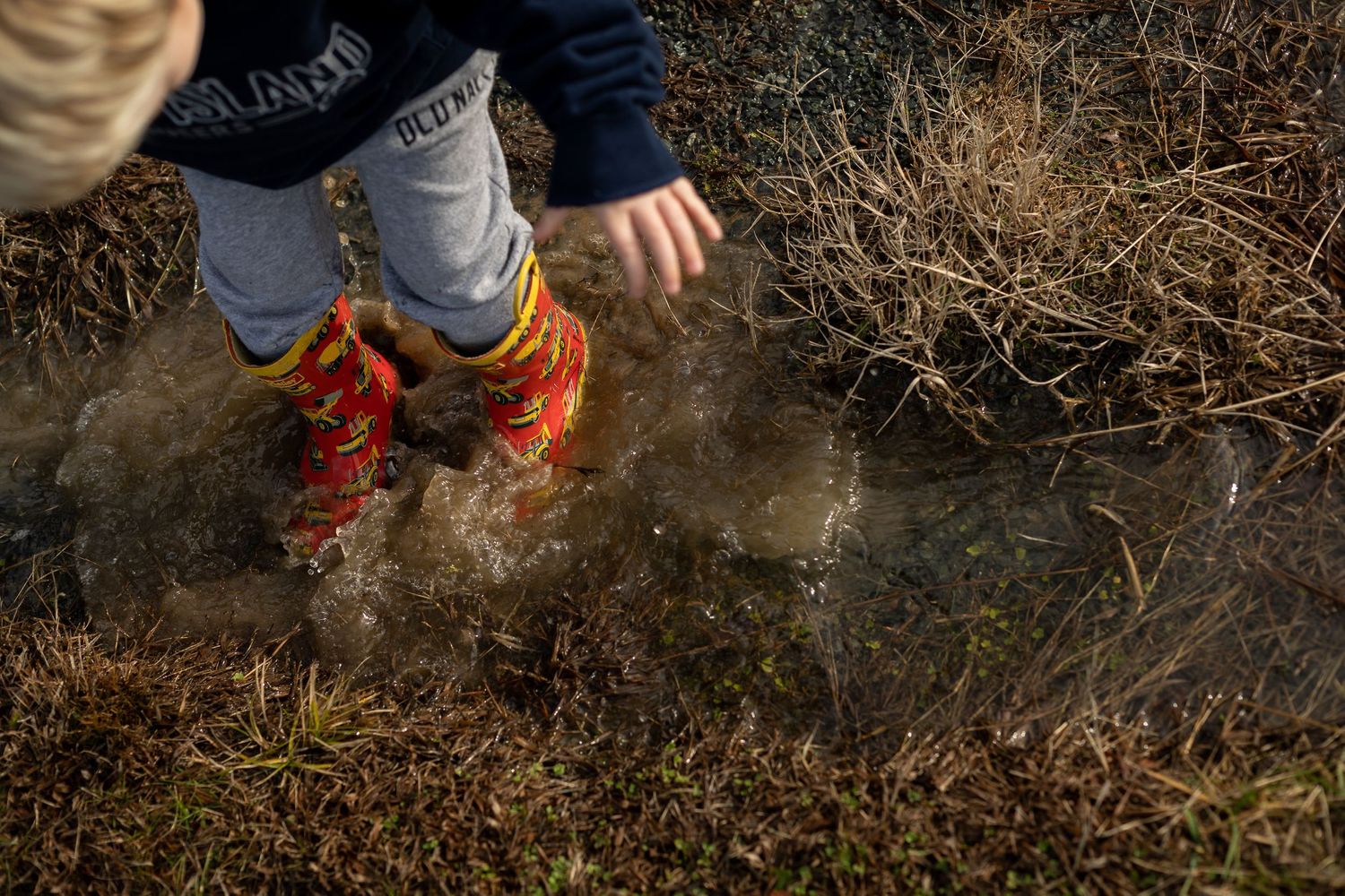 Orange boots splashing in a muddy puddle creating a dramatic spray.