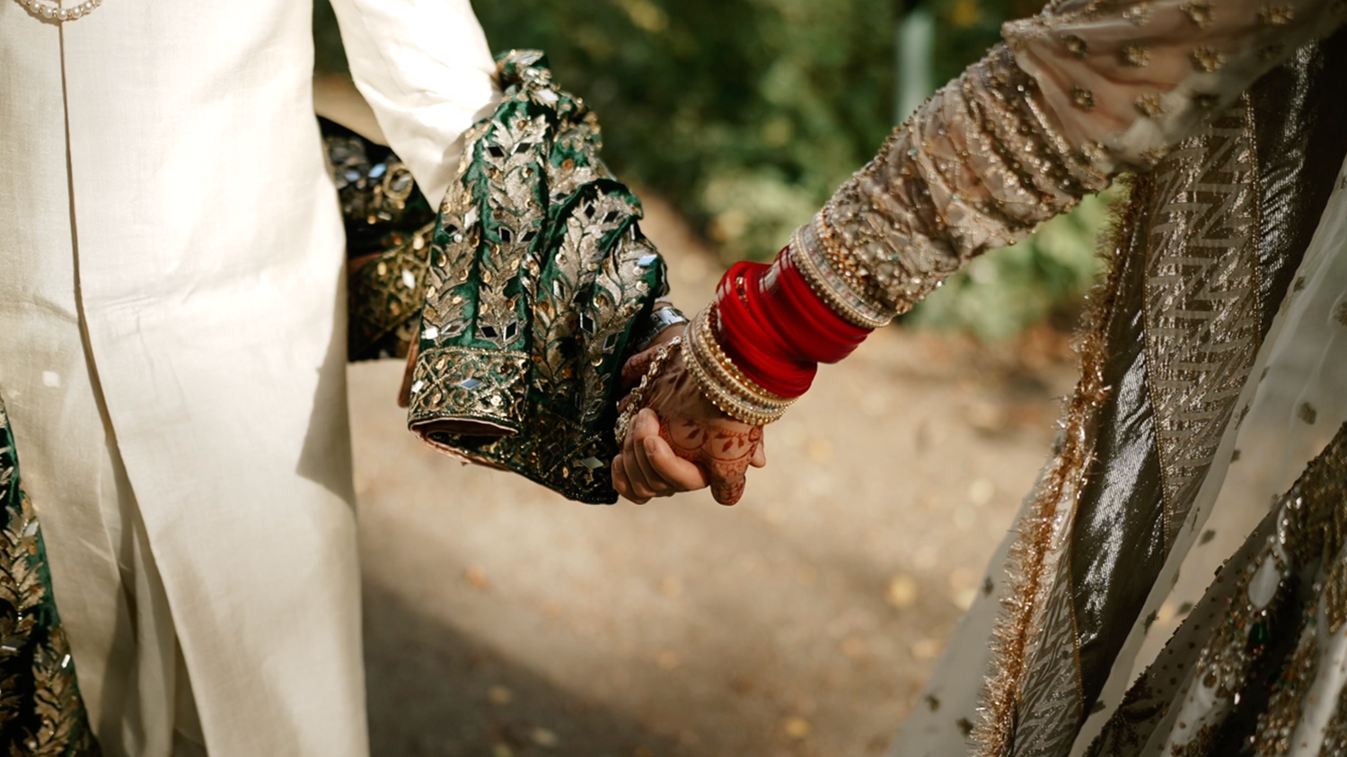 Close up of ornate traditional wedding attire with hands clasped together.