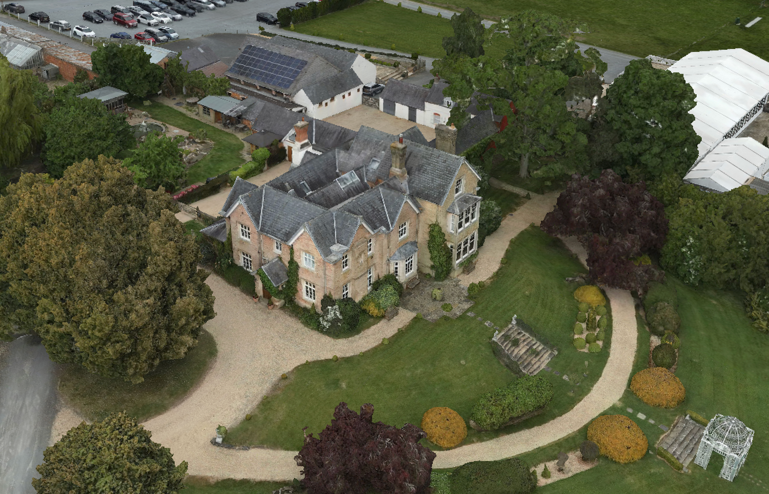 Aerial view of a grand mansion with circular driveway surrounded by manicured gardens.
