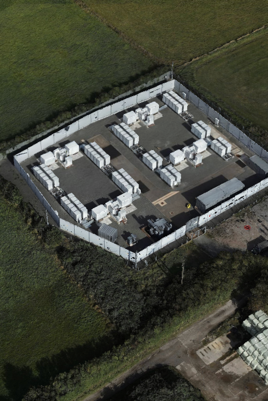 Aerial view of industrial facility with white storage tanks arranged symmetrically within concrete walls.