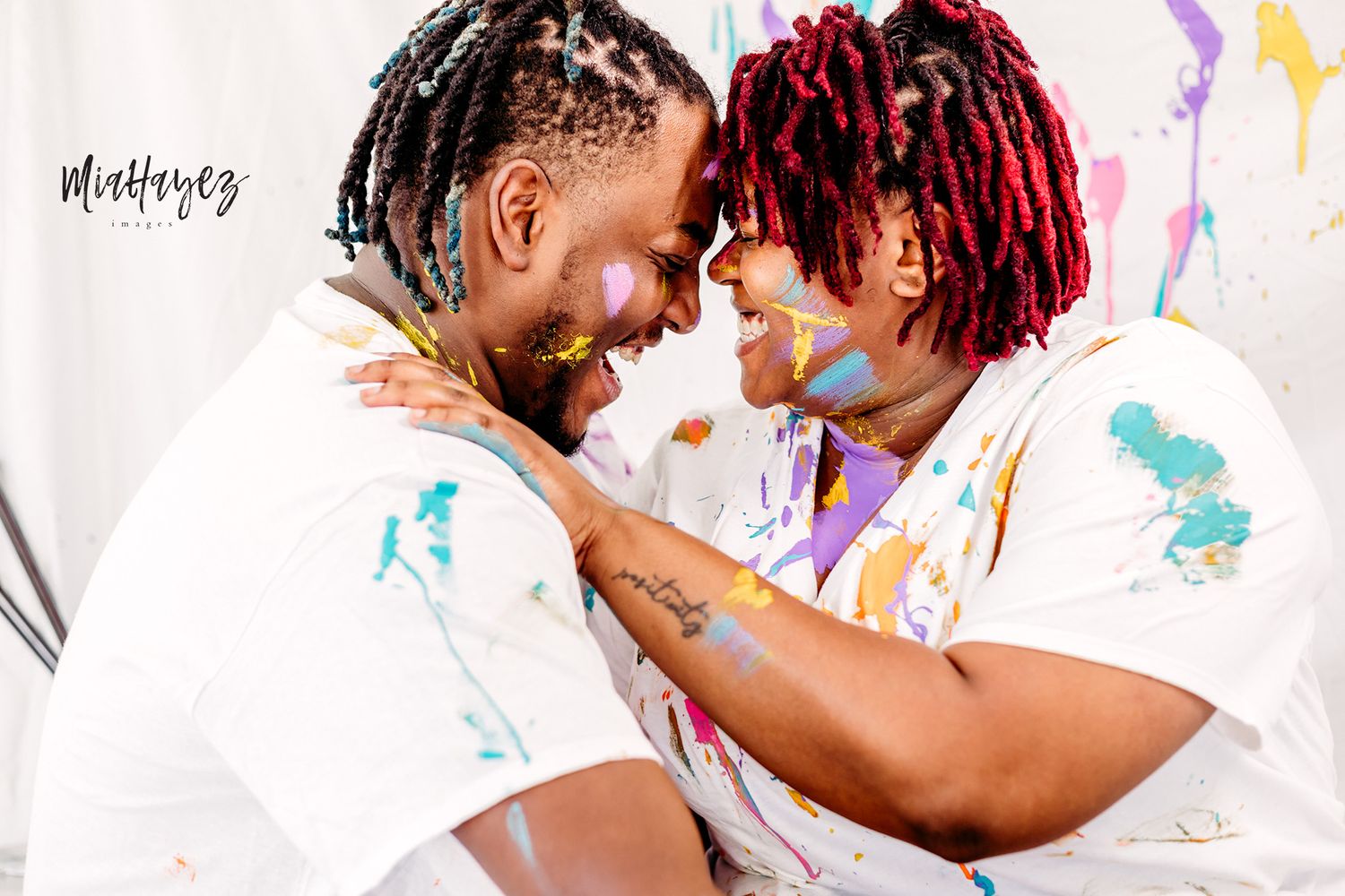 Colorful paint splatter photography session with playful poses against white backdrop.