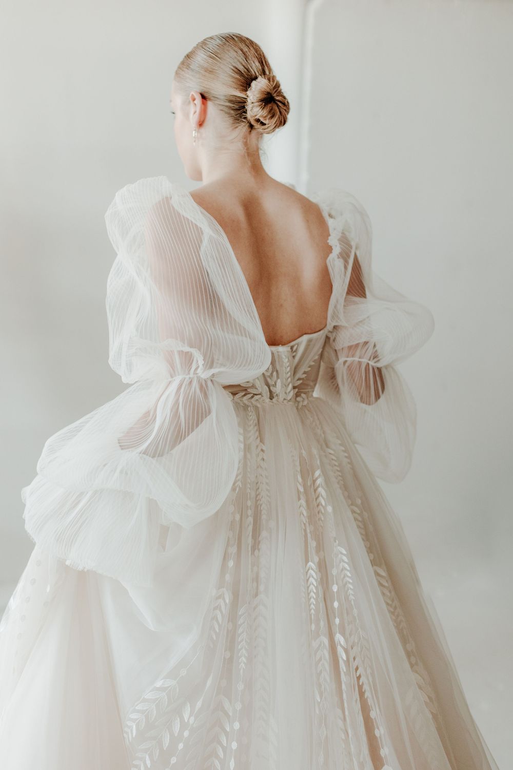 Elegant wedding dress with sheer puffy sleeves and low back design showcased in a romantic bridal photoshoot.