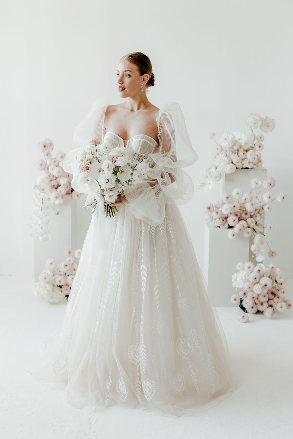 Full-length bridal portrait in romantic tulle gown with white and blush floral bouquet.