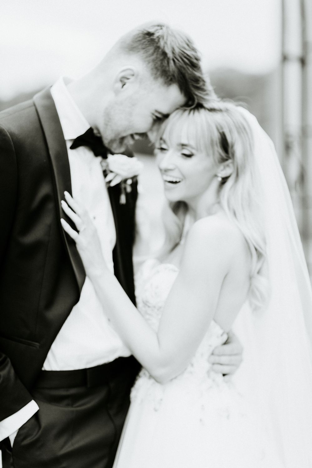 Black and white photo of a joyful couple sharing an intimate moment on their wedding day.