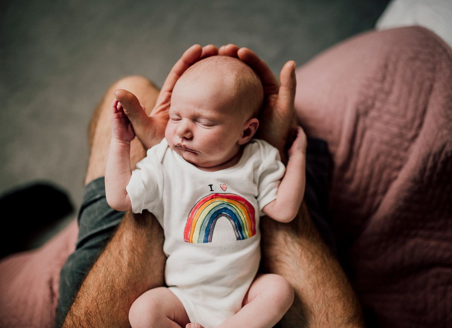 Lifestyle newborn photography session featuring baby in rainbow onesie on brown couch. Worcestershire Wedding photographer.