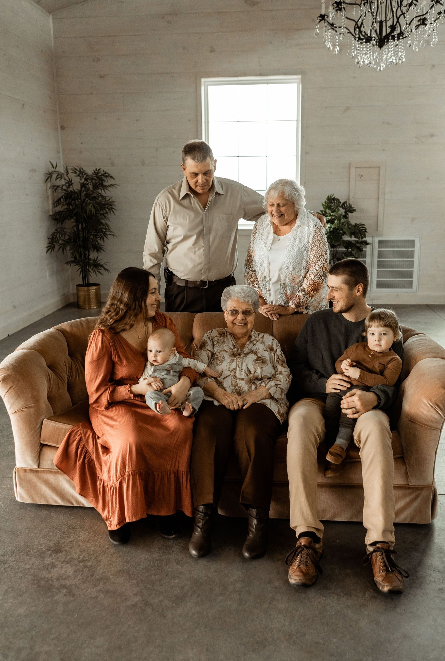 Multi-generational family gathering on cozy sofa in bright minimal room.
