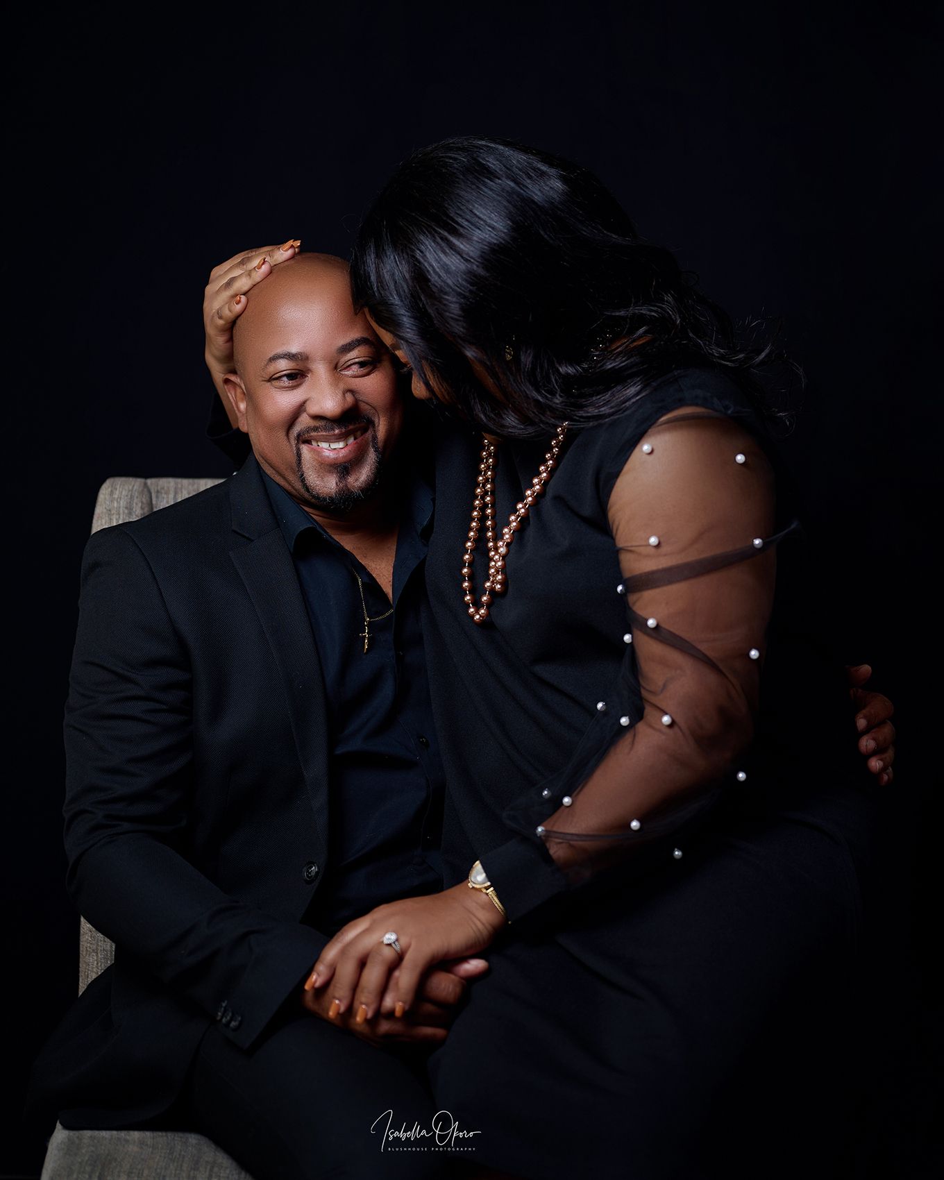 Loving couple portrait showing affection while seated in dark formal wear.