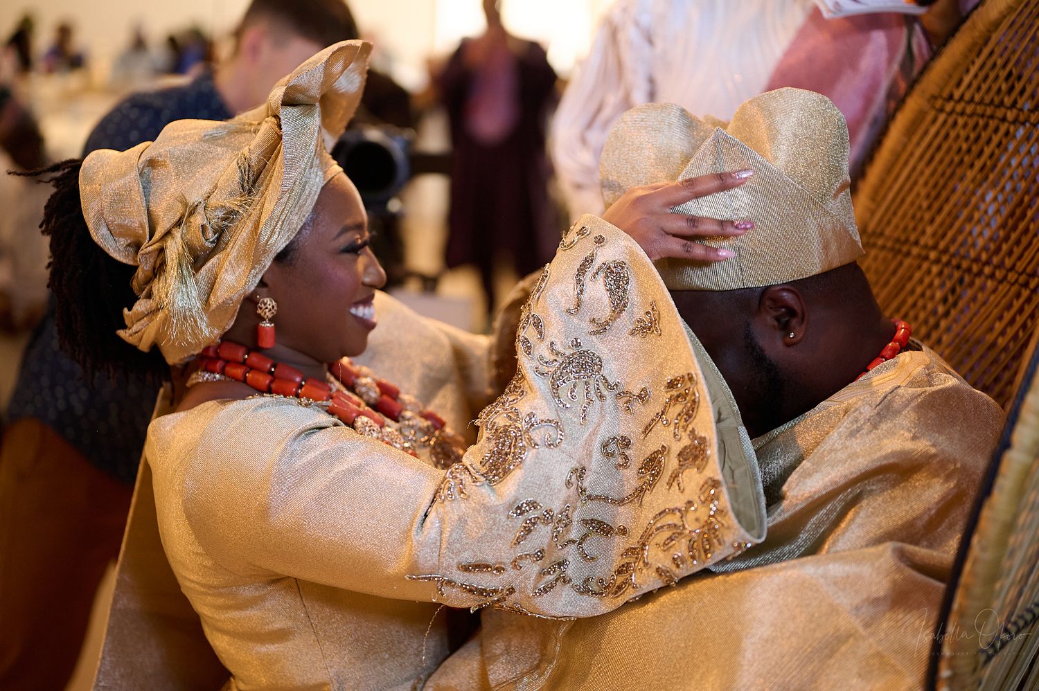 A celebratory moment captured between two people in traditional West African formal wear.