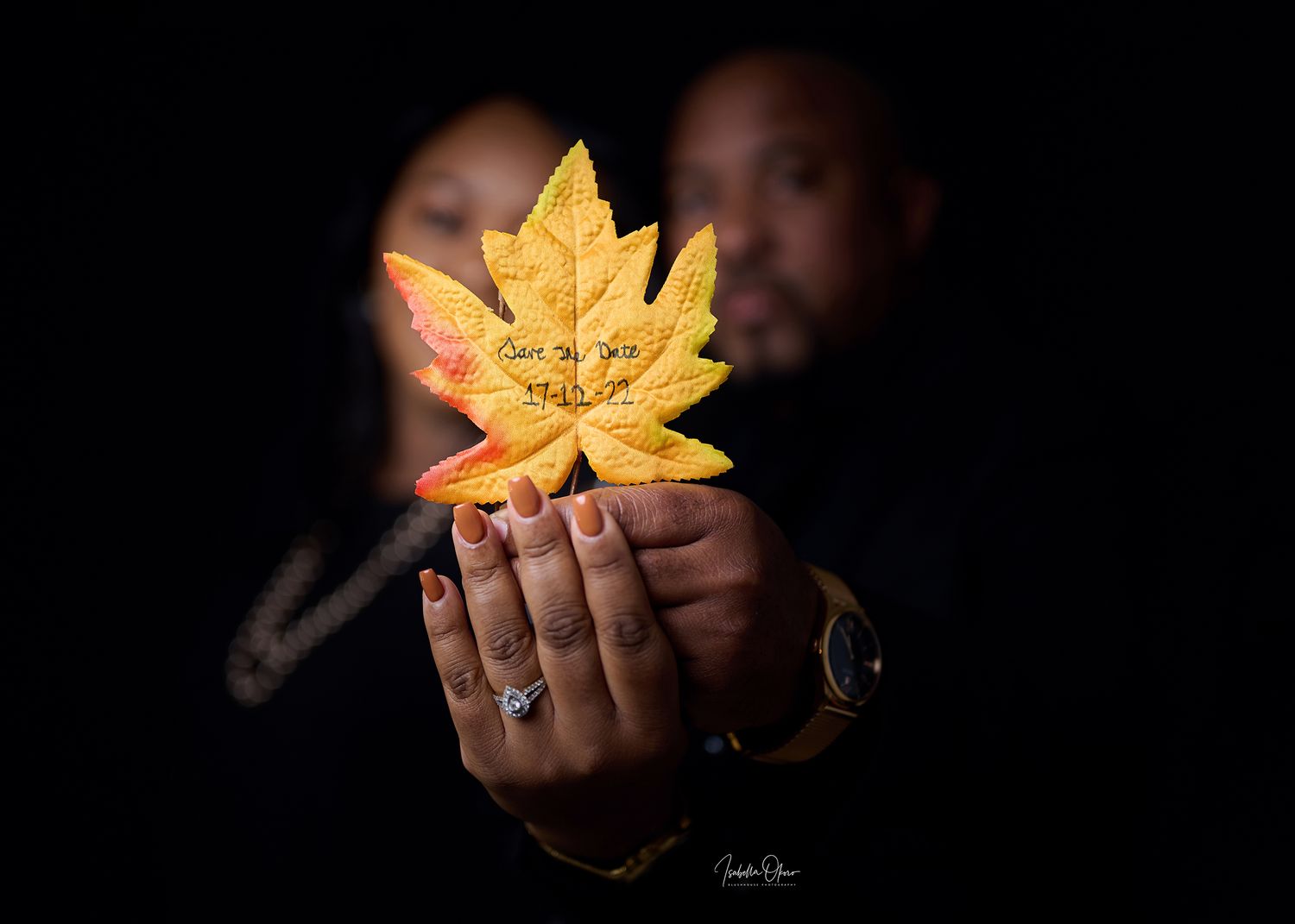 Artistic photo of hands holding glowing golden maple leaf against black background.