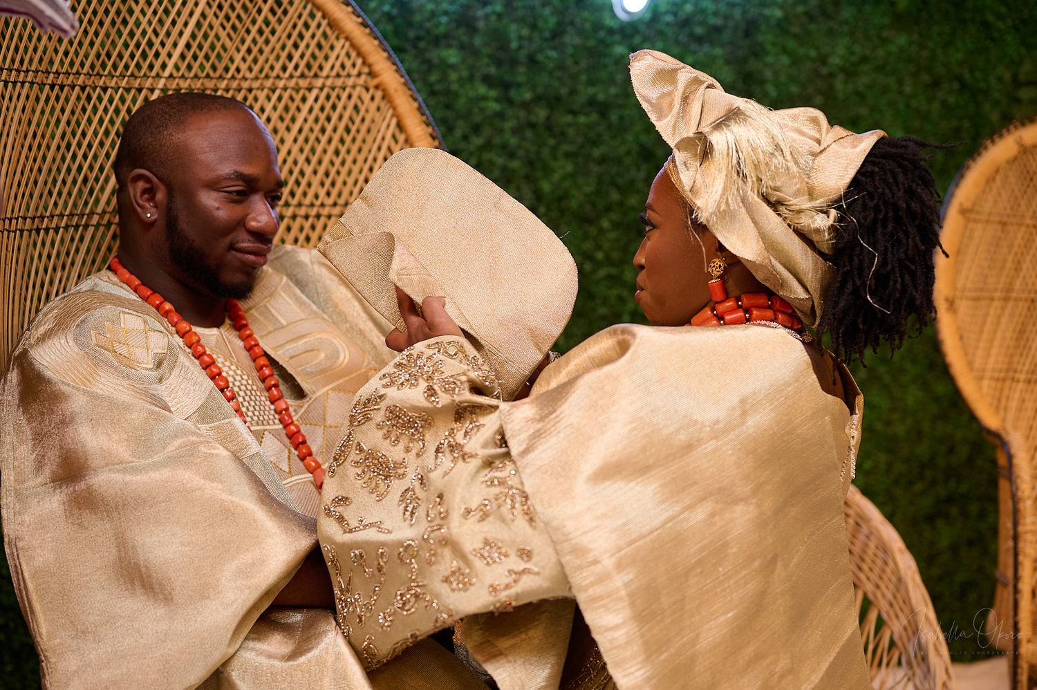 A couple in cream-colored traditional Nigerian attire celebrates during a ceremony.