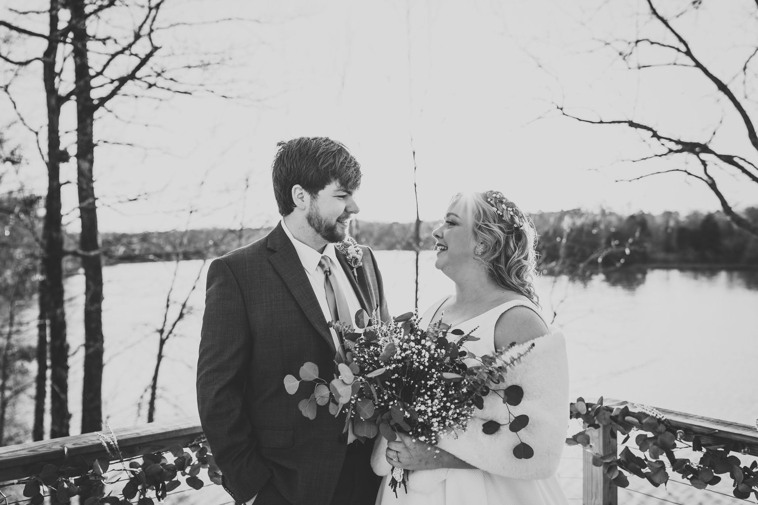 Wedding party walks along a wooden boardwalk surrounded by bare winter trees.