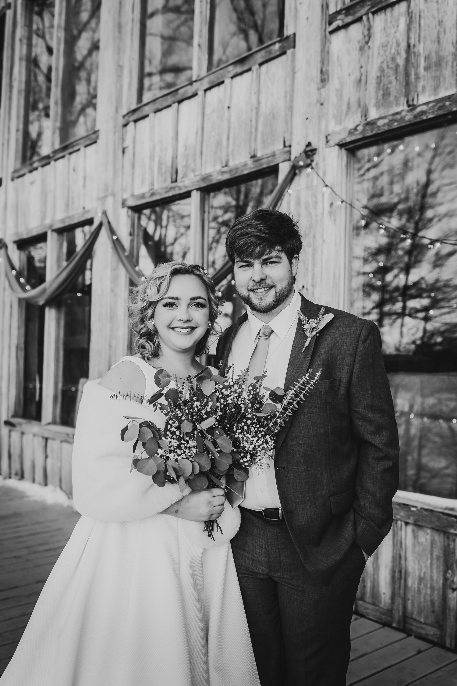 Winter wedding portraits against rustic wooden walls with natural lighting.