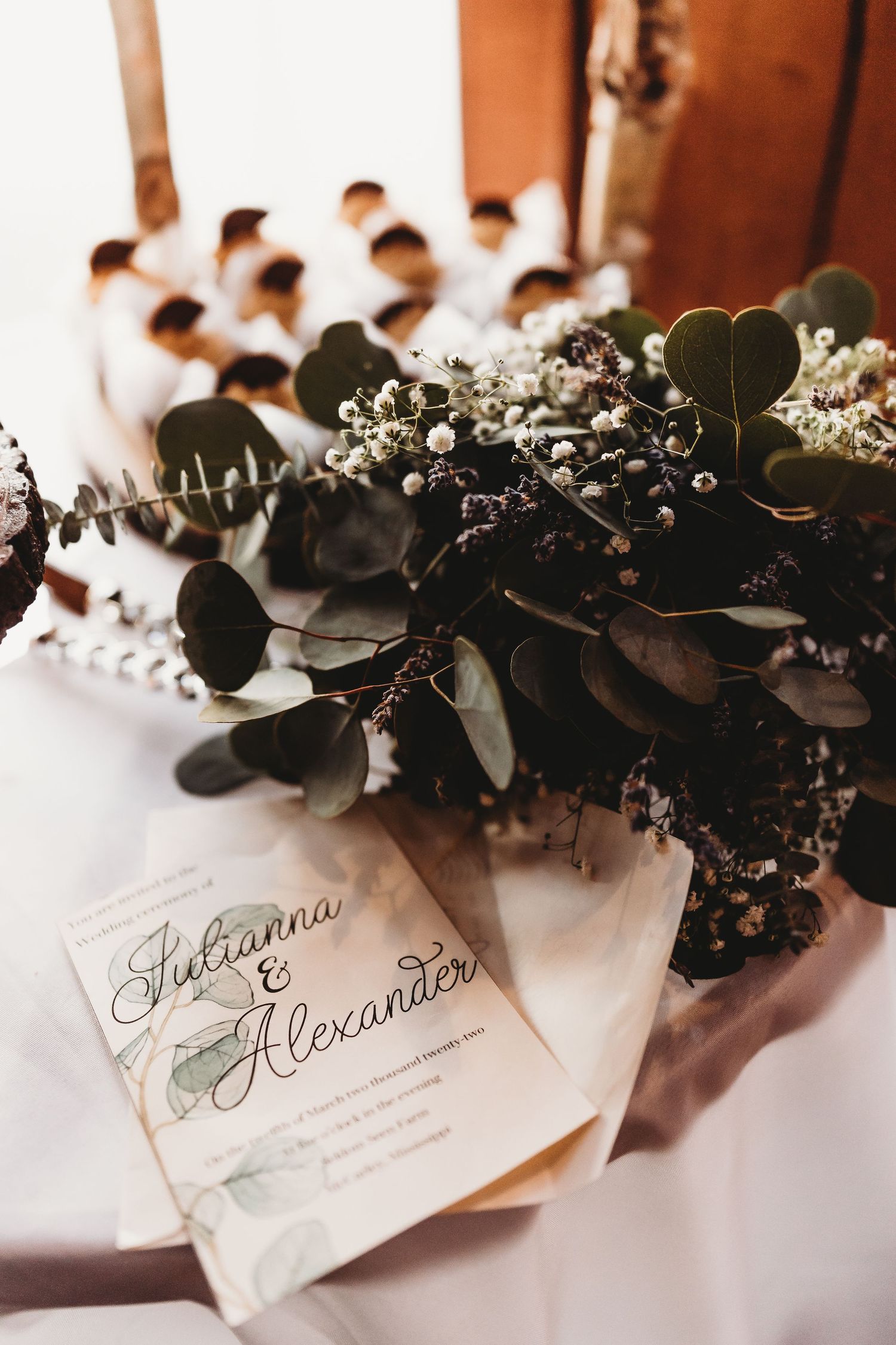 Wedding place cards with greenery and eucalyptus decorations on white tablecloth.