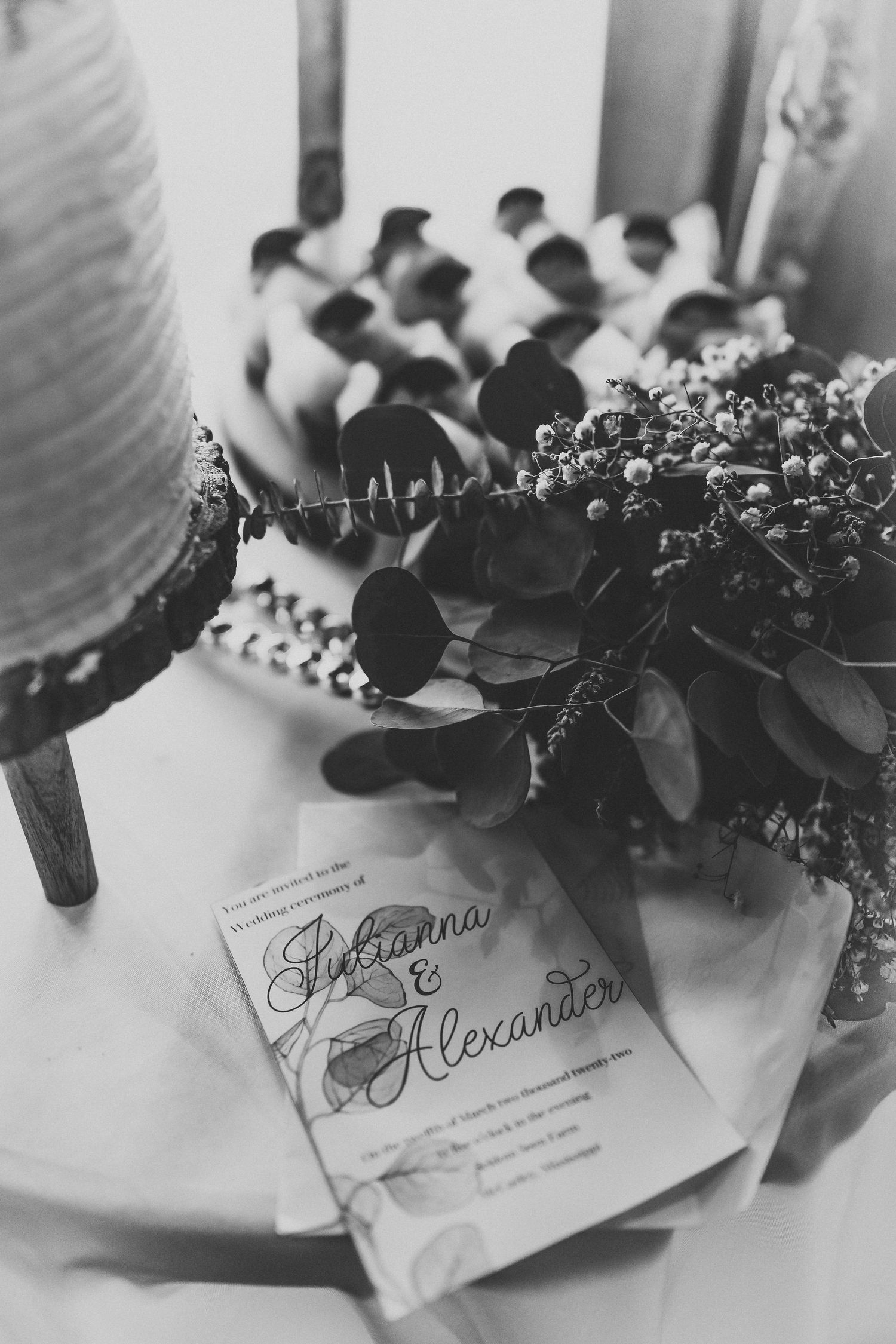 Black and white photo of wedding place cards decorated with dark foliage.