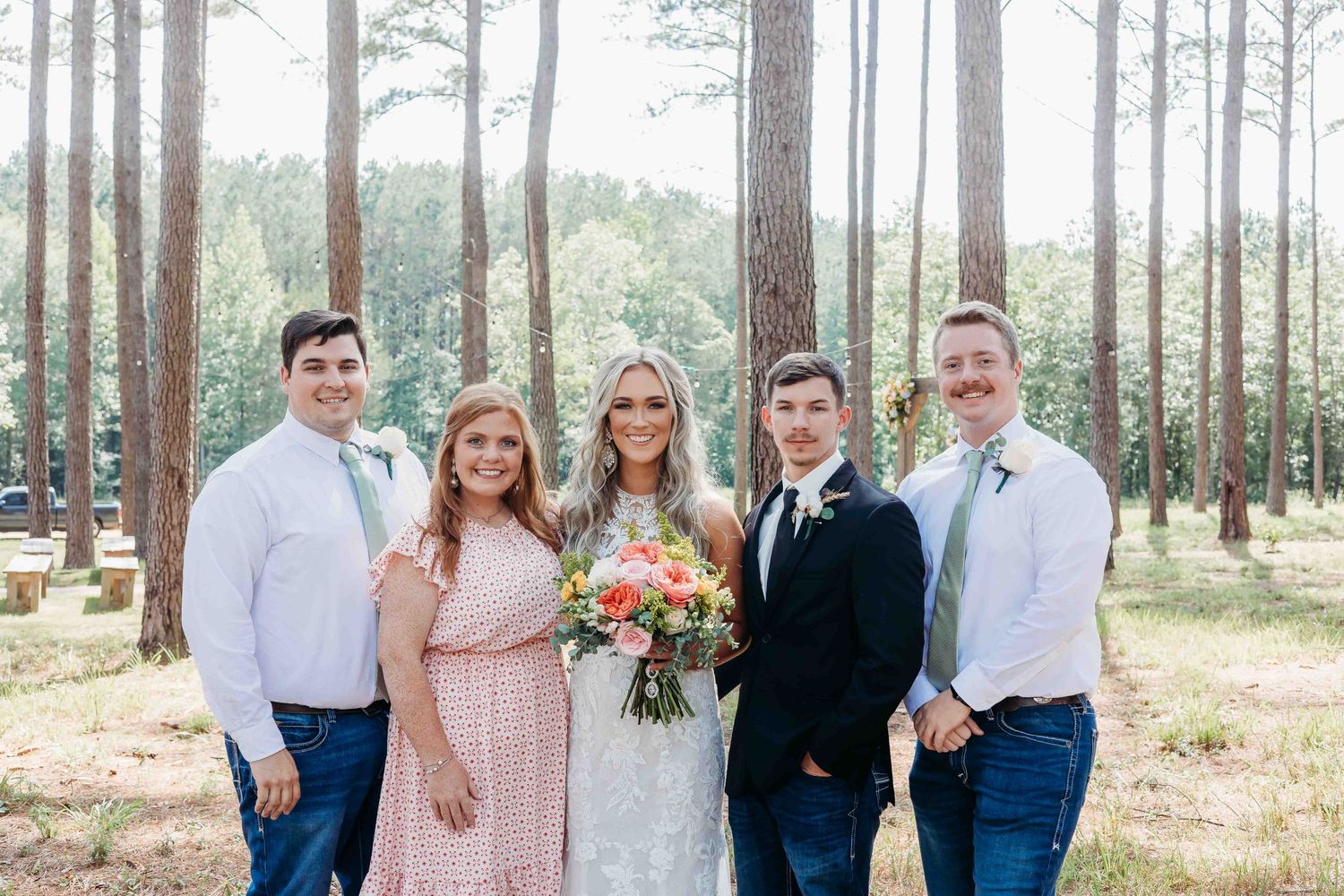 Wedding party poses for casual portraits among pine trees in natural outdoor setting.